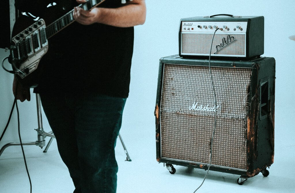A guitarist playing in front of a worn vintage Marshall amp