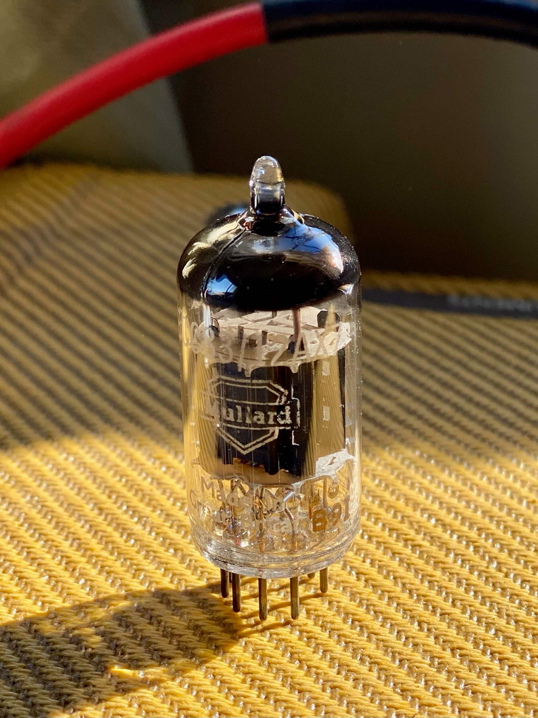 A vintage Mullard tube on top of a tweed amplifier
